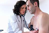 A female doctor checking the heart health of a man with a stethoscope.