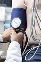 Cardiollogist monitors blood pressure of patient during cardiology strees test.