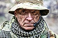 Close-up portrait of brutal commando veteran, experienced army commander or officer with dirty face, wearing camouflage bonnie, shemagh, tactical radi...