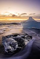 Broken ice from washed up Icebergs on Jokulsarlon black beach at sunset Jokulsarlon South east Iceland.