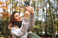 Portrait of Happy woman making selfie in the autumn park full of yellow leaves .