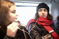 friends sharing headphones, sharing listening to music or podcast in bus
