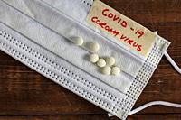 Medical protective mask Corona virus alias covid-19 on wooden background with pills.