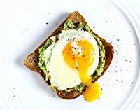 Toast with avocado and egg on white plate.