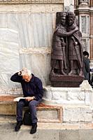 Man reading by the statue of the four tetrarchs outside St Mark´s Basilica in the Piazza San Marco, Venice, Italy.