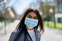Girl with a mask to avoid contagion walking down the street. Coronavirus concept.