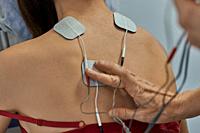 Electro stimulation in physical therapy to a young woman. Medical check at the shoulder in a physiotherapy center. Tens therapy.