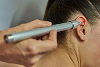 Laser therapy. Physical therapist treating patient ear.