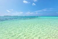 Empty tropical beach background. Horizon with resort island, sky and white sand under clear water in Maldives.