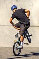 A BMX Freestyle Team biker shows careful balance in a skill demonstration in a Huntington Beach, CA, parking lot.