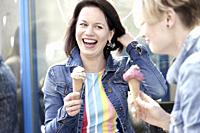 Two happy female friends eating vegan dairy-free and sugar-free ice cream cone made with cashew nuts and dates
