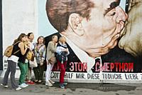 Tourists taking pictures at the ´´Fraternal Kiss´´ mural painting by Dmitri Vrubel. Berlin, Germany.