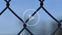 Camera sliding around wire fence with blue sky