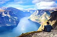 Man sitting on cliff edge alone enjoying aerial view backpacking lifestyle travel adventure outdoor summer vacations in Norway top of beautiful mounta...