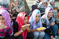 Girls wearing Islamic headscarves relax and snack on sweet corn in Sultanahmet Park, Istanbul.
