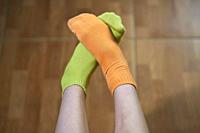 girl's feet with orange and green colored socks.