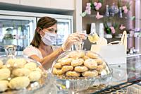 female bakery owner preparing an order and wearing a protective mask due to the corona virus pandemic.