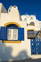 typical Santorini house with white wall, and blue and yellow windows.