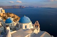 typical white church with blue dome in the city of oia in santorin.