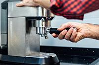 Detail of man's hands preparing an espresso.