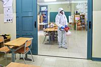 Worker in protective suit disinfect interior of the school.