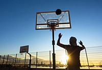 Mature man playing Basketball on outdoor court at sunrise in Las Palmas, Gran Canaria, Canary Islands, Spain. Model released.
