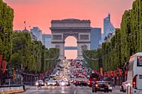 France. Paris. Dense traffic on the Champs Elysees. Triumphal Arch. Pink sunset.