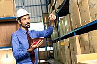 White caucasian middle east warehouse manager hold digital tablet to do inventory in warehouse distribution center environment. For business warehouse...