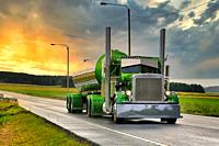 Green Peterbilt 359 tank truck year 1971 of Fredrik Biehl moves along wet highway after rain, with dramatic sunrise sky. Composite image.