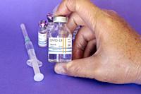 hand holding COVID-19 coronavirus vaccine isolated on purple background.