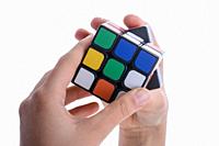 Child holding a Rubik's cube in hand on a white background.