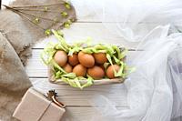 Basket with eggs and spring decor on a white wooden background.