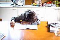 child with his head on the school book desperate cannot do his homework, in the home kitchen.