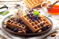 Homemade crispy Belgian waffles served with blackberries honey and icecream.