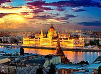 Hungarian parliament on riverbank of Danube illuminated in evening, Budapest.