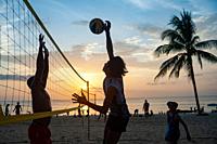 Phuket, Thailand, Asia - A group of locals plays volleyball in the sunset on Karon Beach.