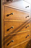 Maple wood dresser with brass metal knobs on drawers in guest bedroom inside an old 1807 cottage style house, Quebec, Canada.