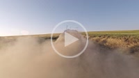 Dust behind a vehicle driving on a rural road through farm fields in the Palouse farming area of eastern Washington State, USA.
