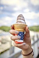 A young girl's hand holding a melting ice cream cone.
