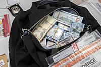 Black duffel bag full of dollar notes in criminal investigation unit, conceptual image.