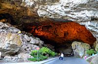 Grand entrance to the Jenolan Caves surrounded by tropical plants and illuminated with artificial lights, near Katoomba, Australia.