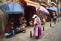 Indigenous woman in front of a touristic art and craft shop at the historic center, La Paz, Bolivia, South America.