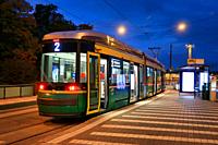 HSL tram No. 2 at tram stop in the morning before dawn, with street lights illuminating the city view. Helsinki, Finland. September 29, 2020.