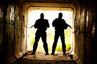Silhouette of special forces operators with weapons in the tunnel.