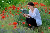 Woman In A Poppy Field Reading and Holding A Book.
