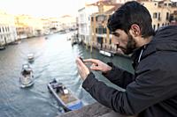 Turkish man on bridge Ponte dell'Accademia at sunrise, morning in Venice, Italy, Europe.