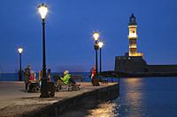 View to the people and the lighthouse by the harbor in Chania city by night, Chania Province, Crete, Greek Islands, Greece, Europe.