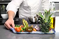 Male Chef Hands Holding plate with vegetables and Fruit. Chef Cooking Healthy Vegetables, fine organic dining. Dieting Culinary Food. High quality pho...