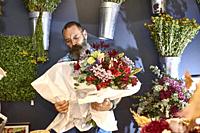 A florist taking care of various flowers and bouquets in his shop.