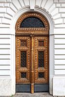 Details of European style classic old-fashion elegant wood carving door panels made of wood and decorated with wrought iron at a white concrete buildi...